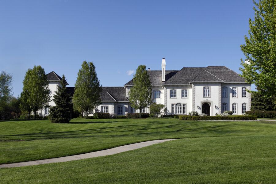 White custom mansion home built on a beautifully landscaped land.